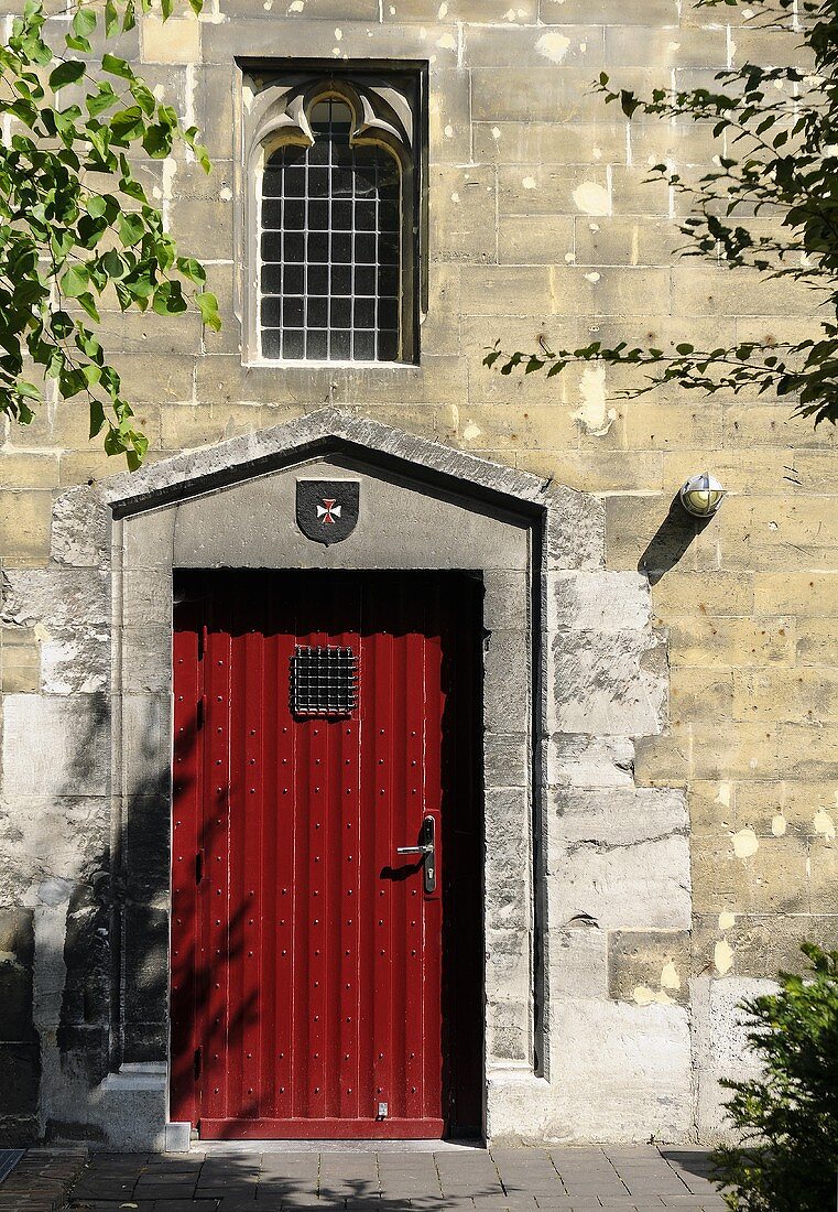 Rote Tür in Steinfassade einer Kirche