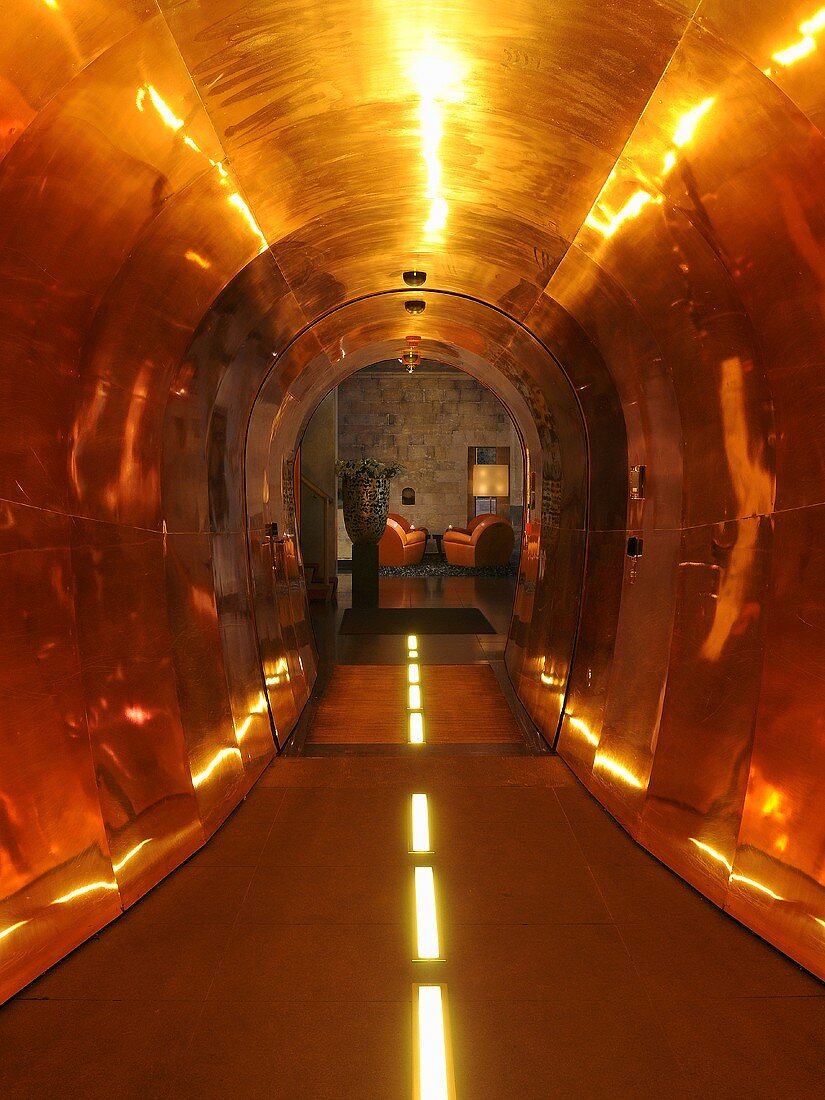Brass-coloured metal cladding in a tunnel-like corridor with artificial lighting