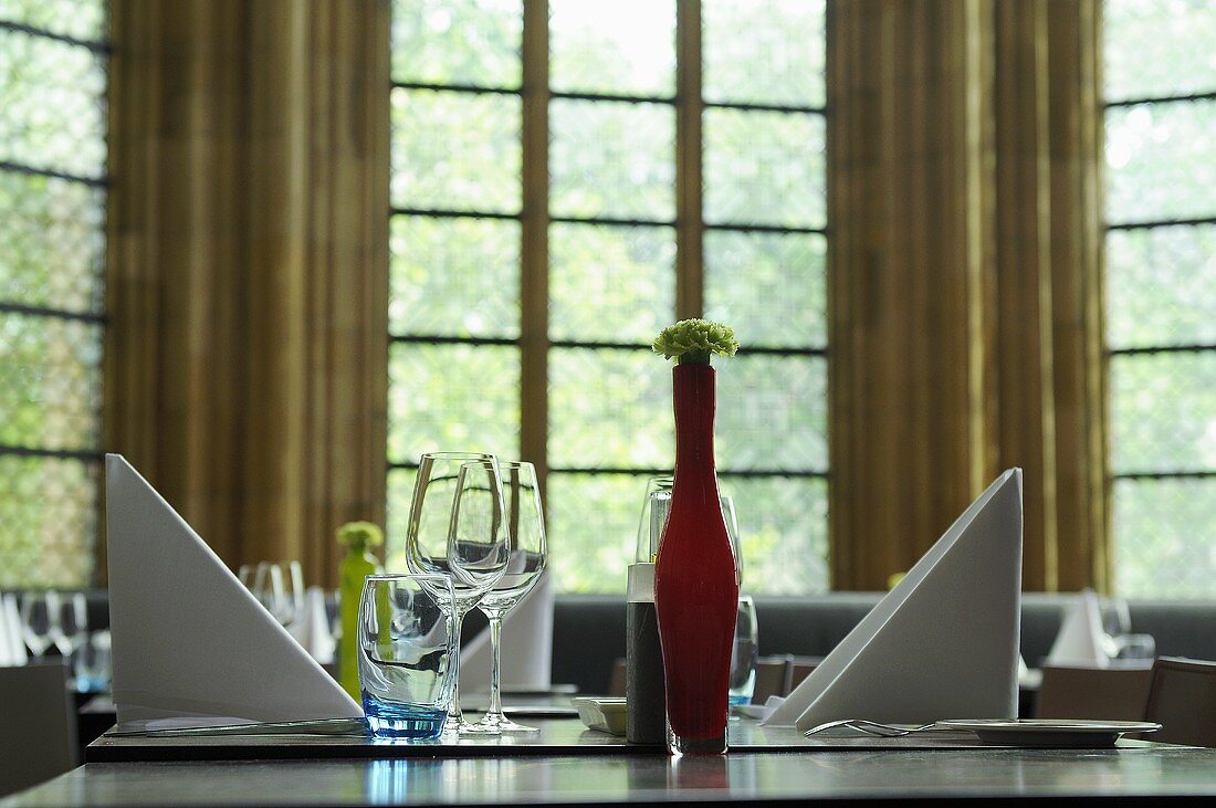 Gedeckter Tisch mit Stoffserviette und Blumendeko mit Blick auf Fenster