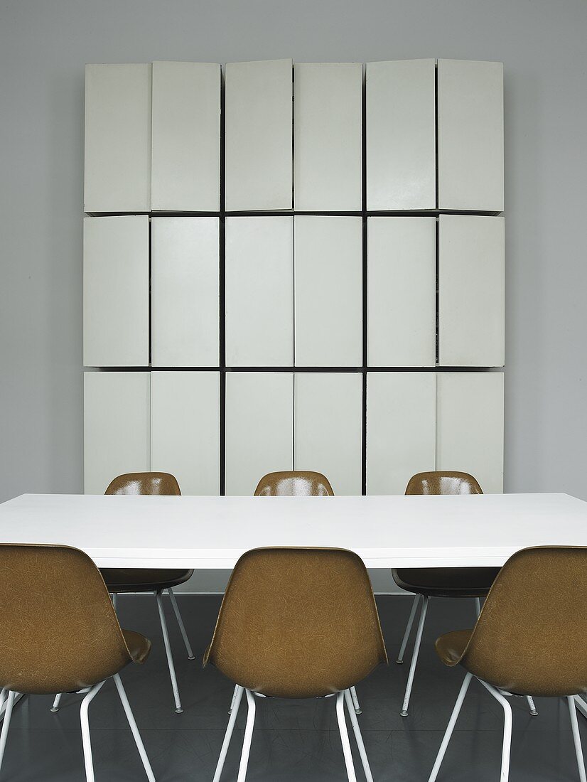 A conference table with brown bucket chairs and a tailor-made wall cupboard with open doors
