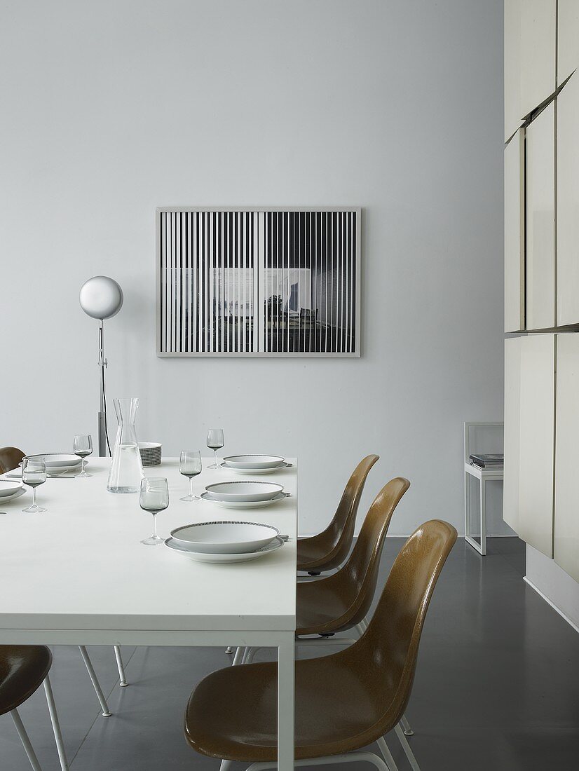 A table laid with brown bucket chairs in a minimalistic room