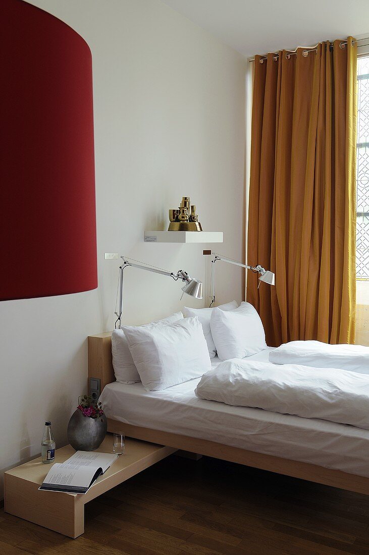 Designer Holzbett mit Nachttischlampen und gelbem Vorhang am Fenster