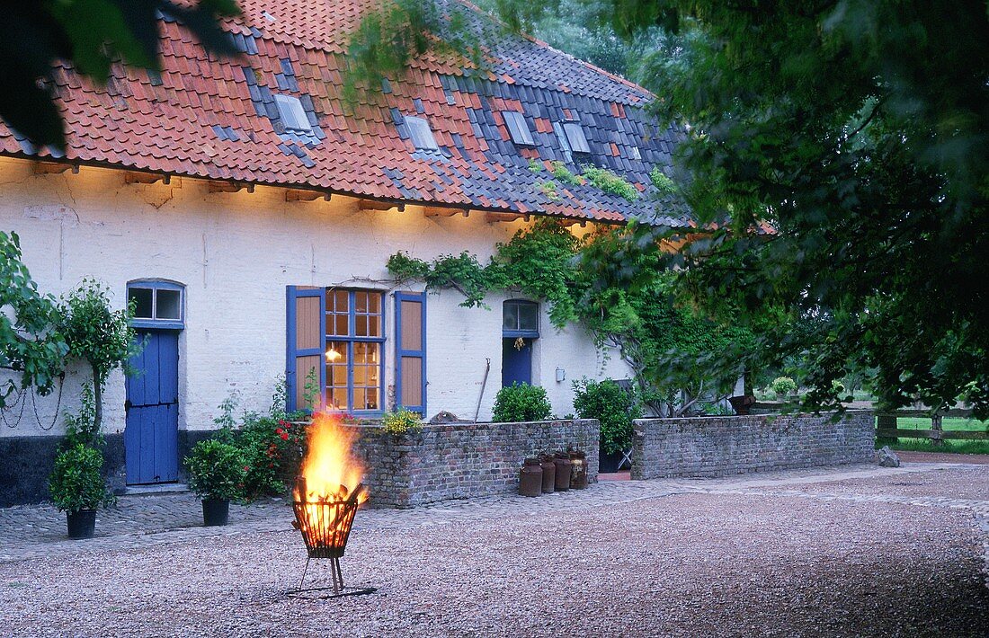 Lodernder Feuerkorb auf Vorplatz eines flämischen Bauernhauses
