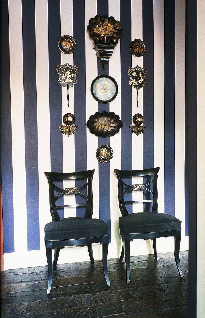 Antique upholstered chairs against a blue and white striped wall