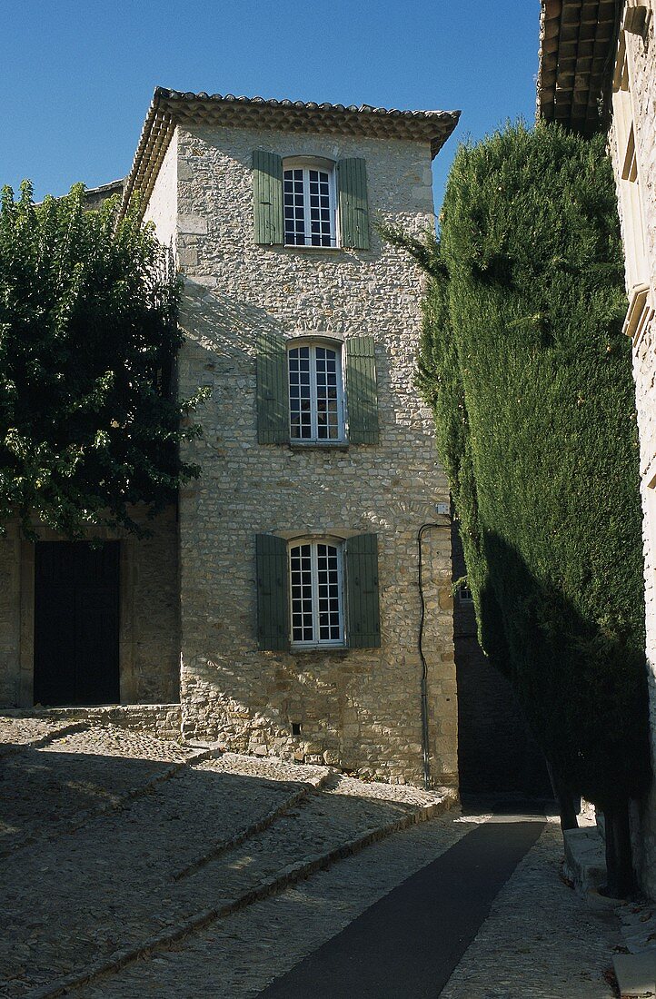 Weg und kleiner Platz mit Bäumen vor Mediterraner Turmhaus mit Sprossenfenstern