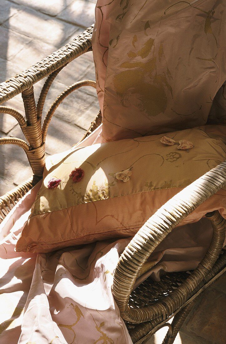 A cushion and a silk cloth on a wicker chair