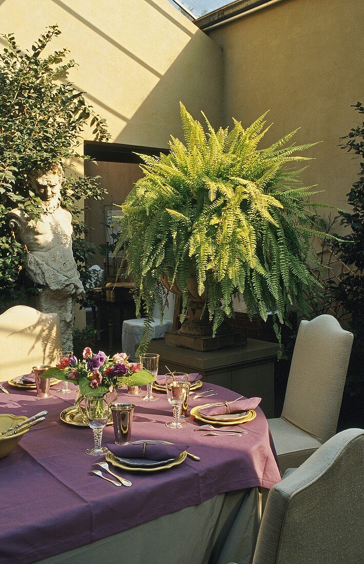 A table laid on a terrace wit plant pots on pedestals
