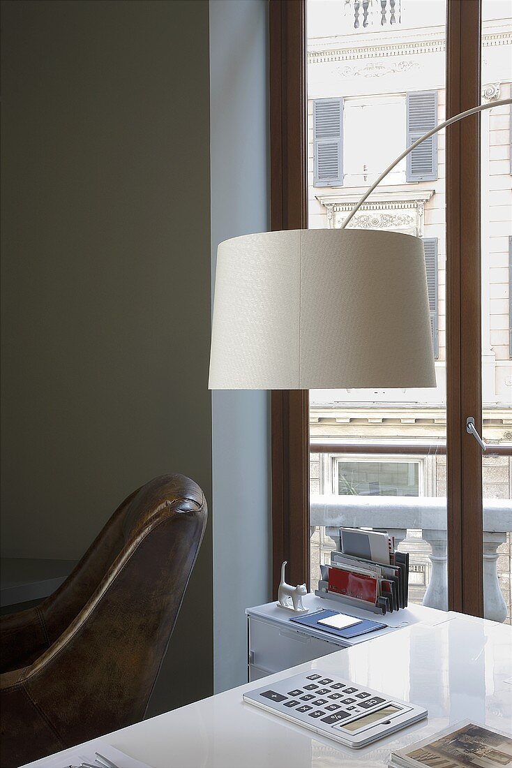 A white lampshade above a table and a window with a view
