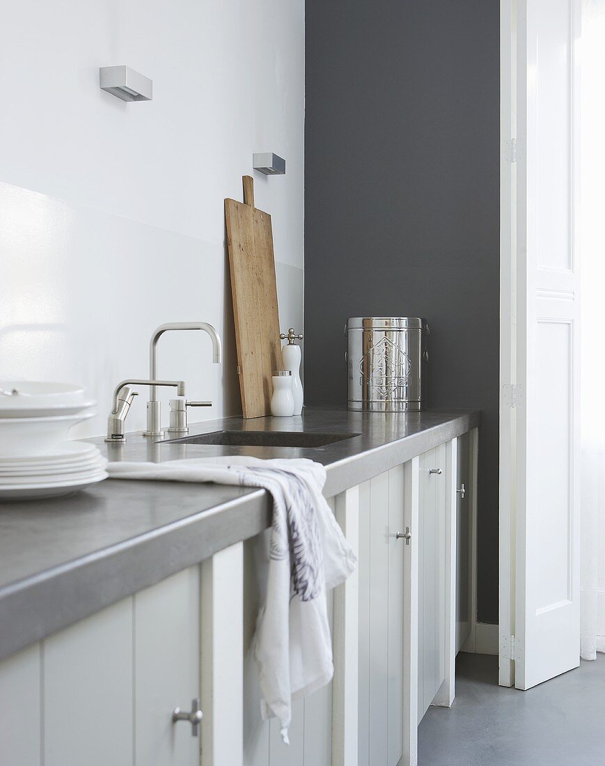A grey kitchen counter with a sink and a cupboard underneath