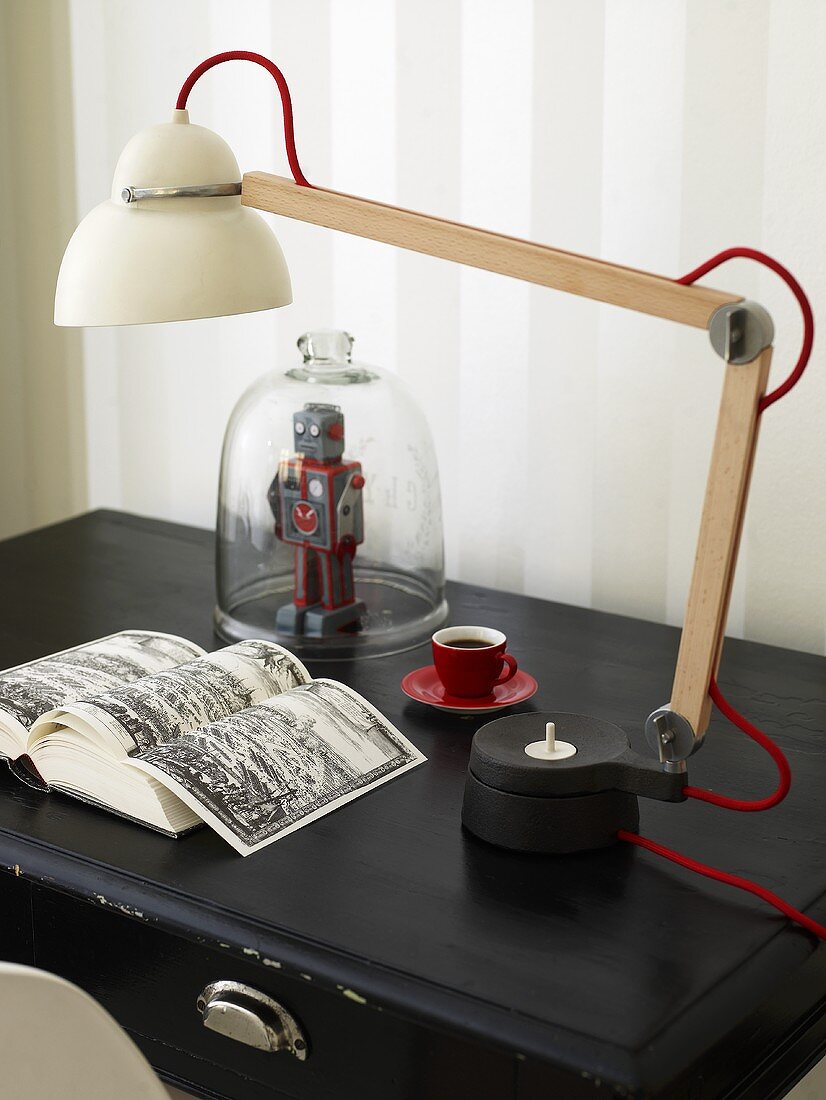 Tischlampe mit Porzellanschirm und verstellbarem Fuss auf schwarzer Ablage