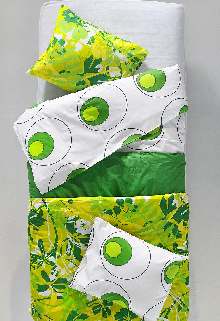 Showroom - Bett mit Kissen und grün weiss gemusterter Bettwäsche