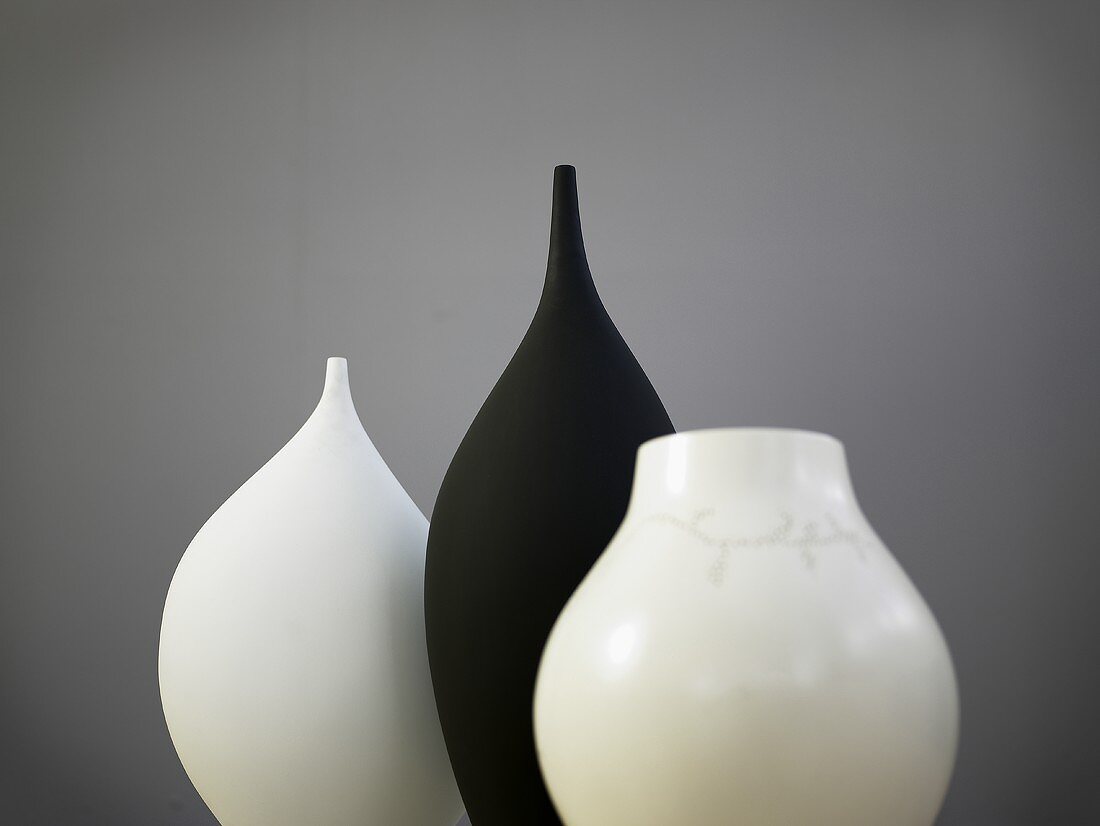 Schwarze Vase zwischen weissen Vasen
