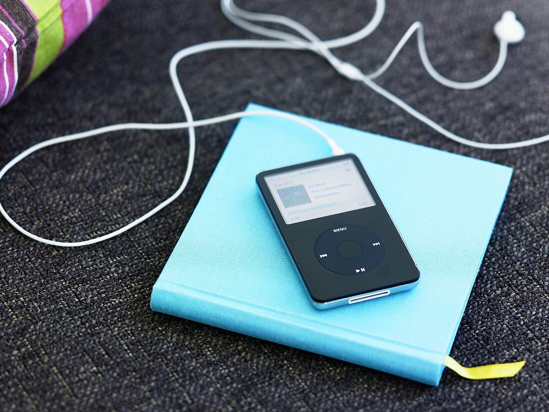 MP3 player with earphones on a turquoise cover of a book