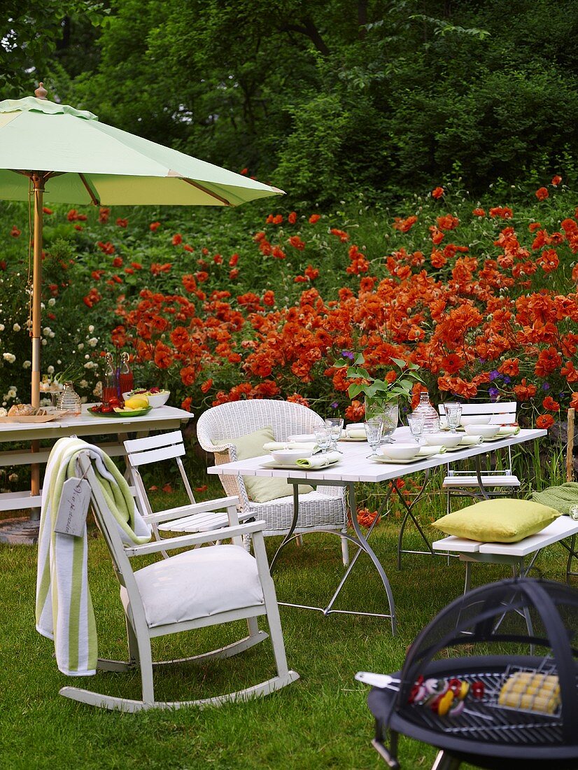 Grillnachmittag im Garten vor rotem Blumenbeet