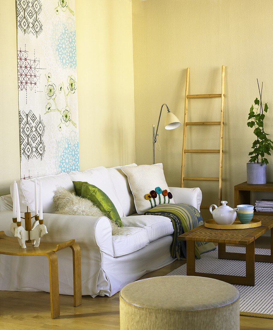 White sofa in front of a wall hanging with wooden coffee table and side table
