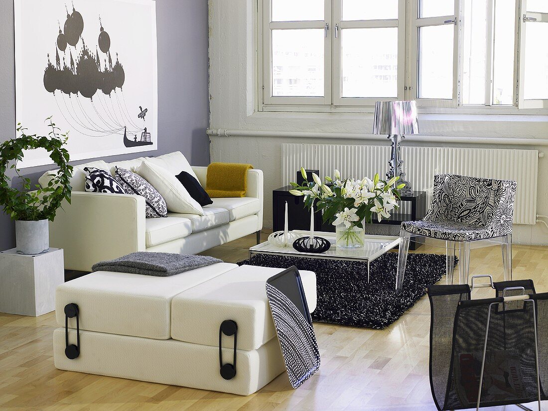 weiße Sofagarnitur mit gemustertem Stuhl und modernem Couchtisch vor Fensterfront