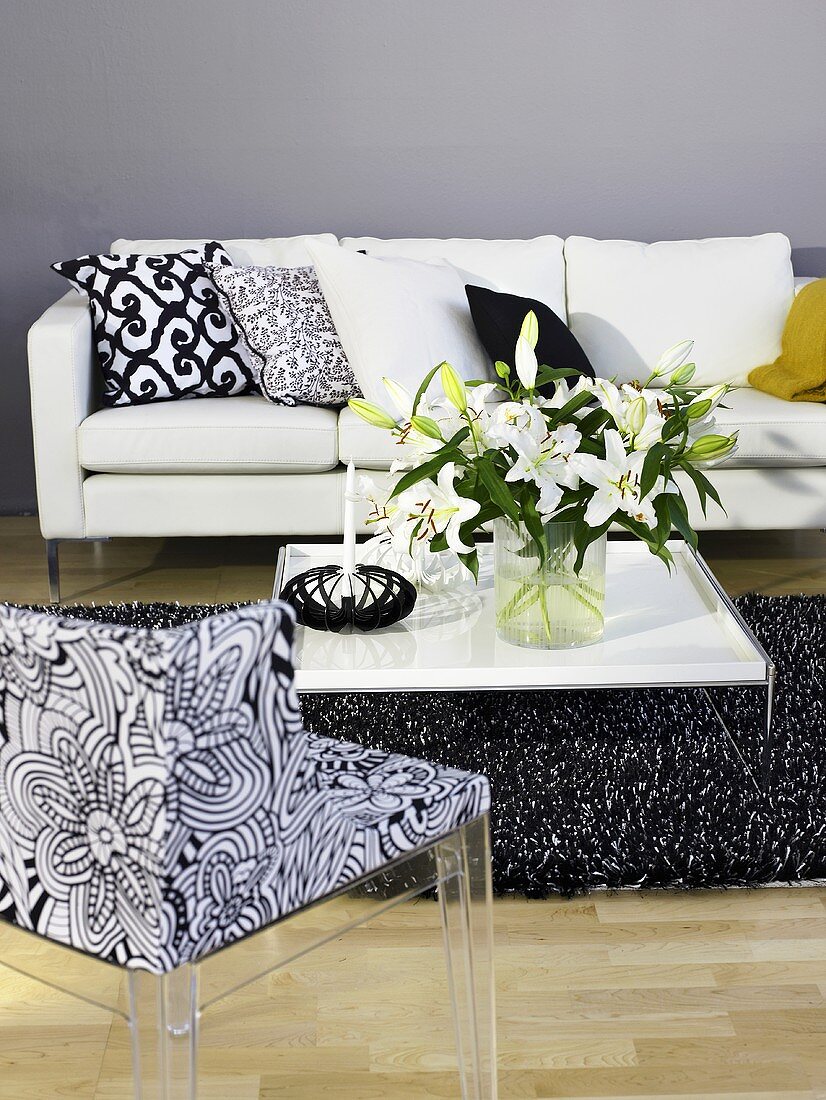 Flower bouquet on a coffee table with patterned chair and white sofa in front of a gray wall
