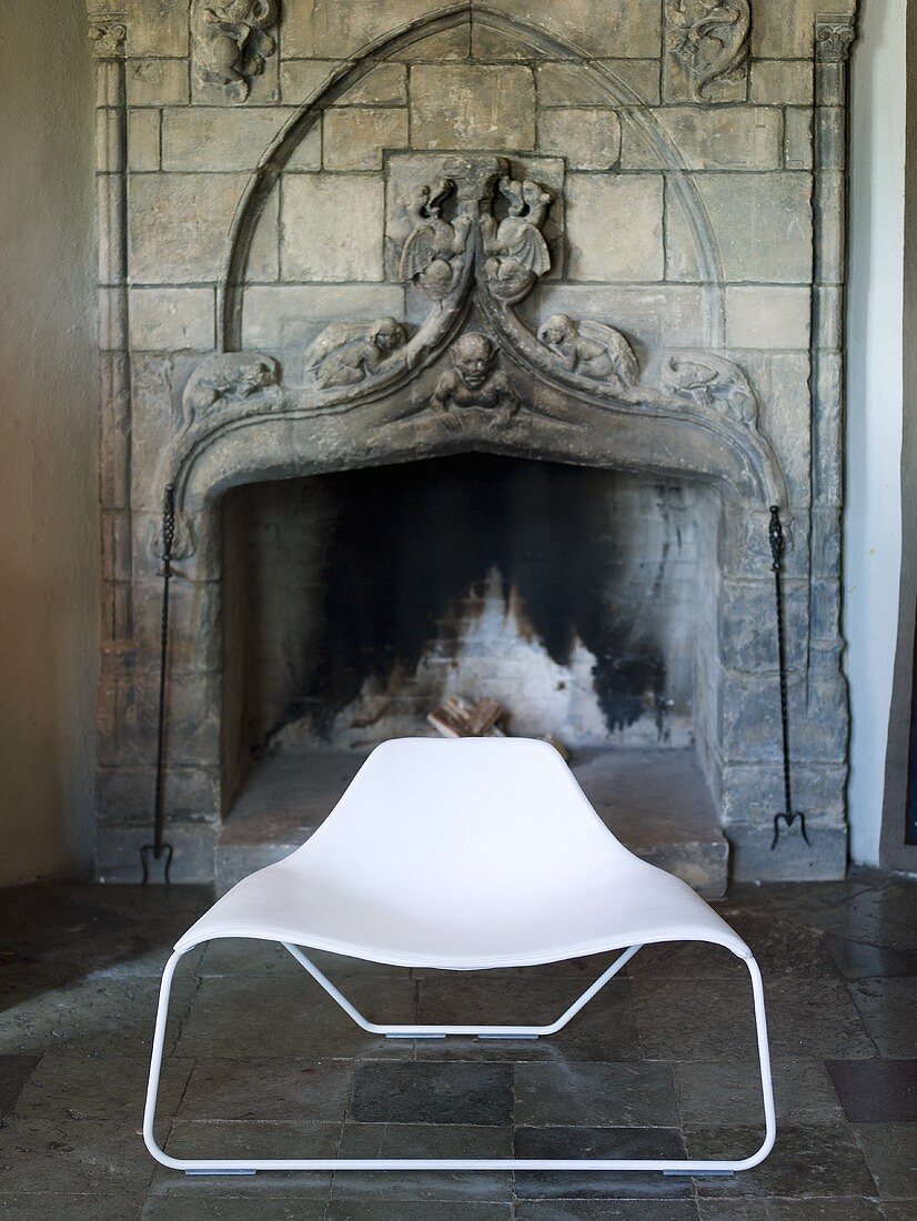 White shell chair in front of an old fireplace in a castle