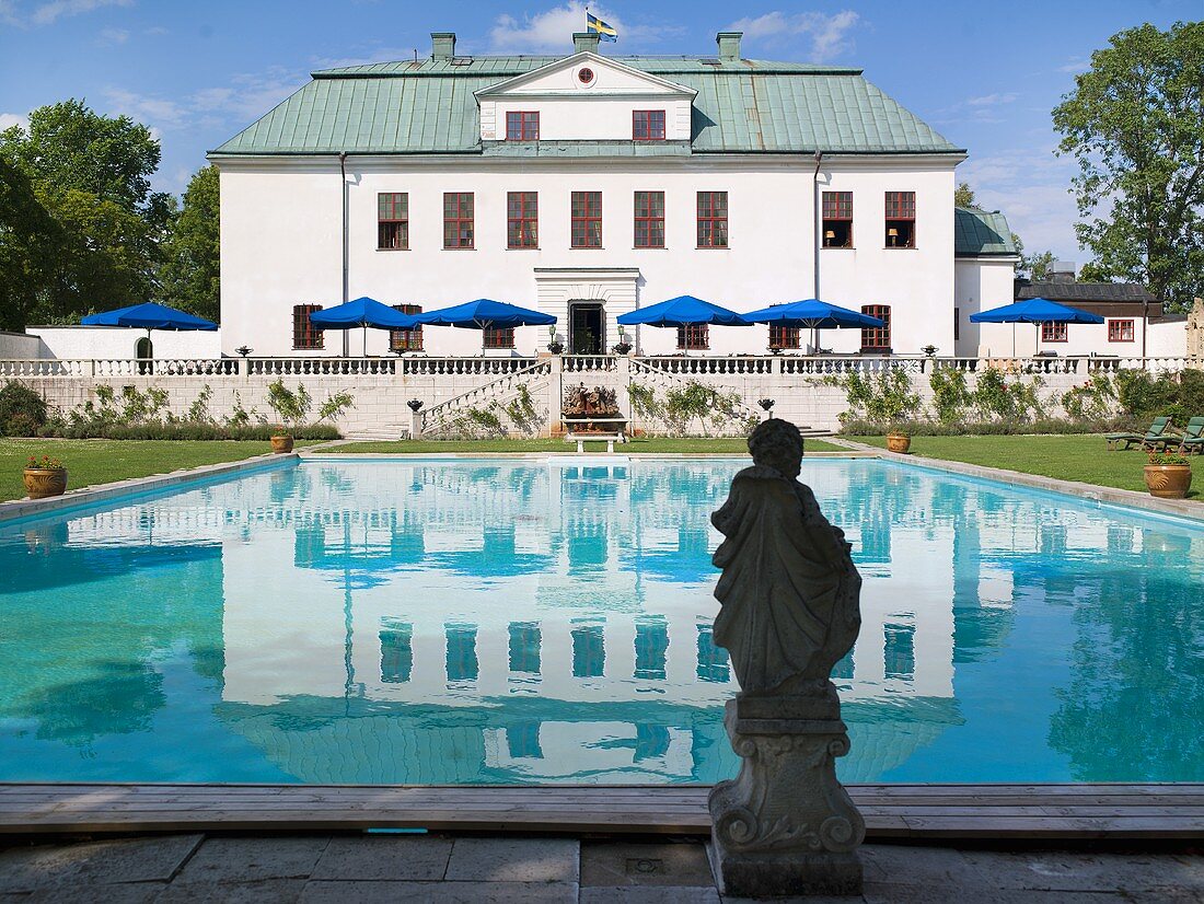 A pool in front of a renovated palace with a terrace