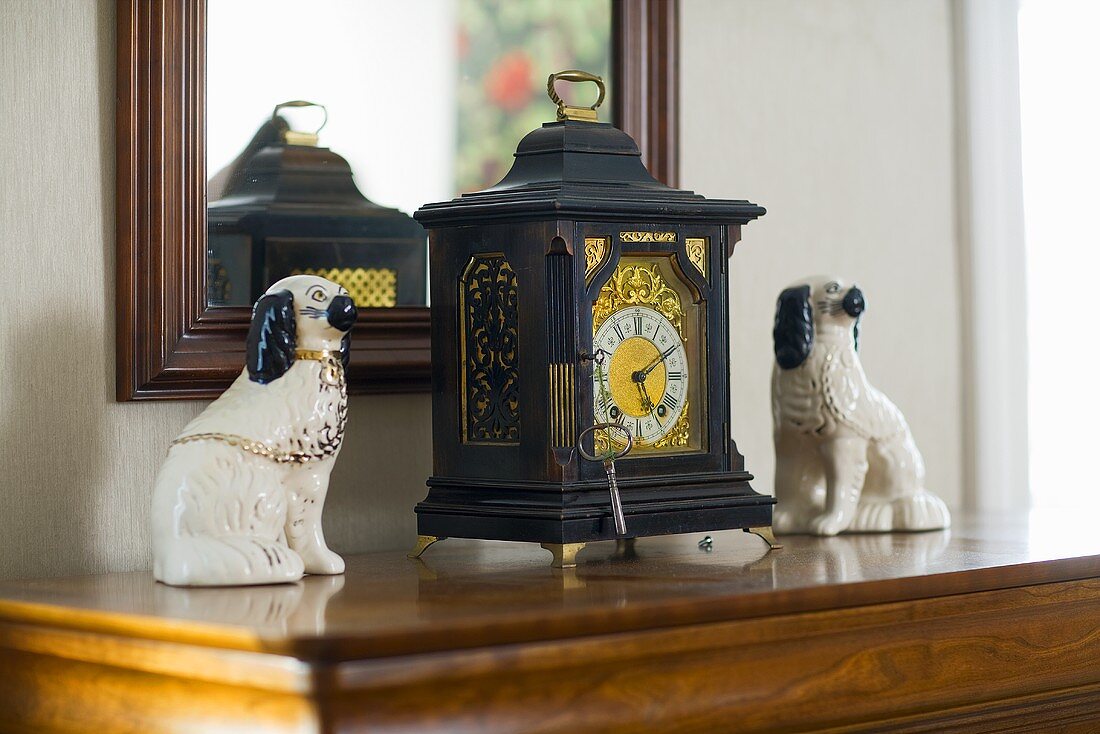 Antike Uhr und Hundefiguren aus Keramik vor gerahmtem Spiegel