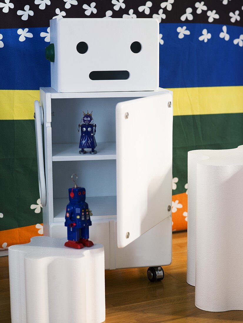 White rolling storage container with open door and a view of toys and white side table in front of a colorful wall hanging