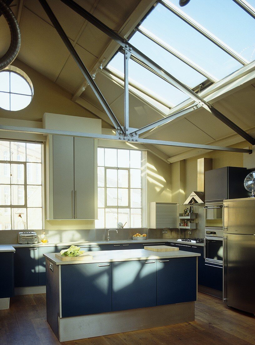Offene Küche mit blauen Schrankfronten im Loft mit Glasoberlicht
