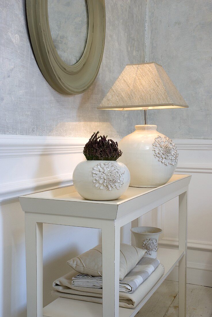 Vase and table lamp made from white ceramic with fabric shade on a table