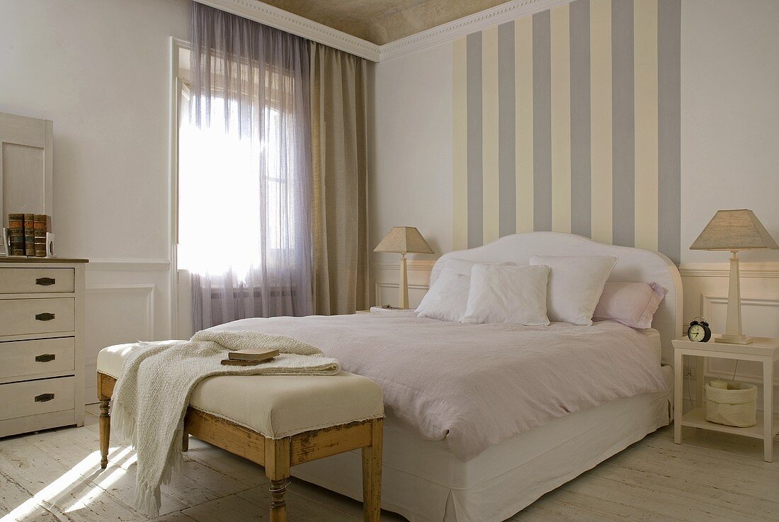 Tapete mit Streifenmuster im Kopfteilbereich des Doppelbettes mit rosa Bettwäsche und gepolsterter Bettbank