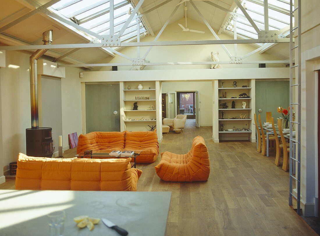 Offener Wohnraum mit orangen Polstermöbeln im Loft mit Oberlicht