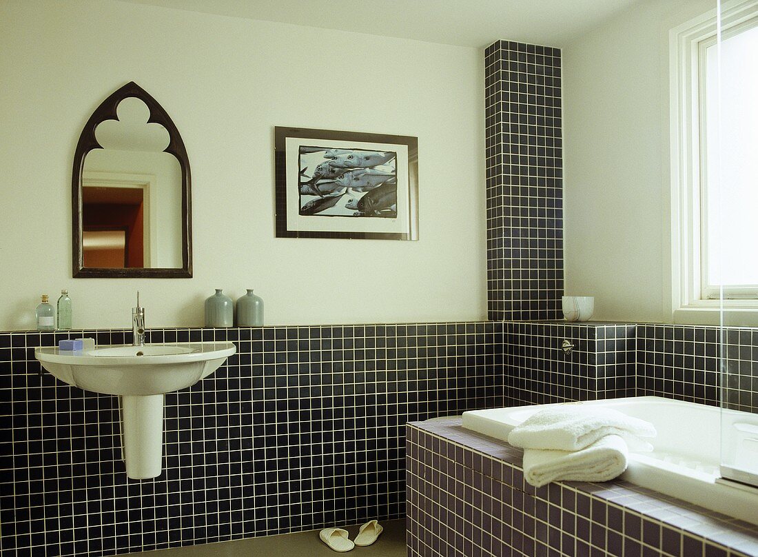 Waschbecken und Badewanne im Badezimmer mit schwarzen und violetten Mosaikfliesen