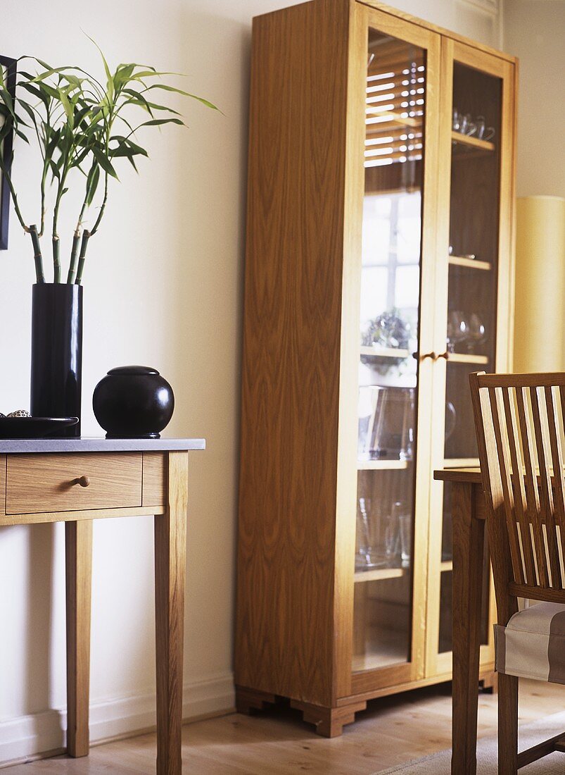 A modern dining room, wooden side table, freestanding display cabinet, flower arrangement,
