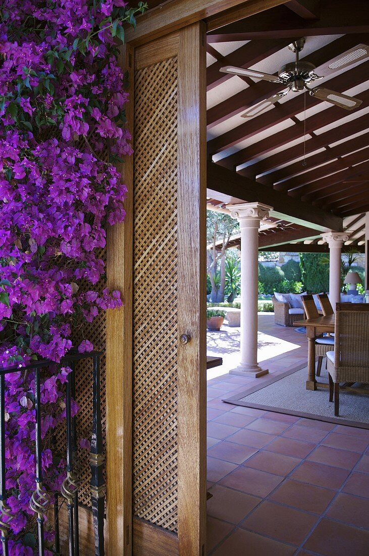 Purple flowers next to wooden sliding door leading to tiled veranda