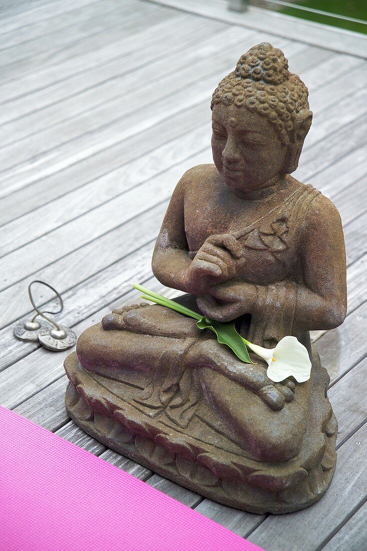 Buddhafigur aus Metall auf Holzdeck