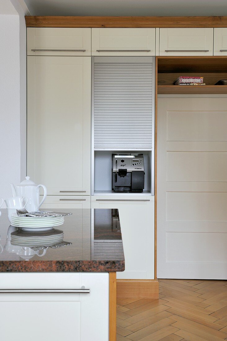 Küchenmöbel mit Arbeitsplatte in Granit vor Einbauschrank mit weissen Fronten