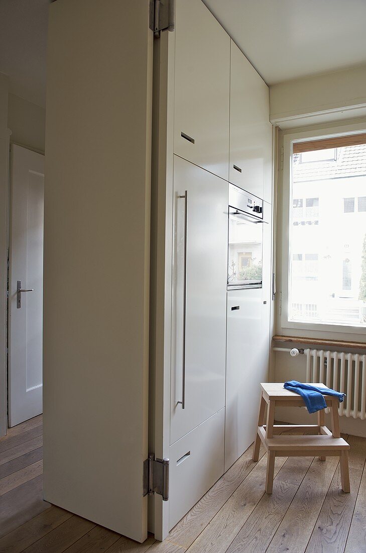 Moderne Küche mit weißem Einbauschrank und Einbaugerät neben offener Tür