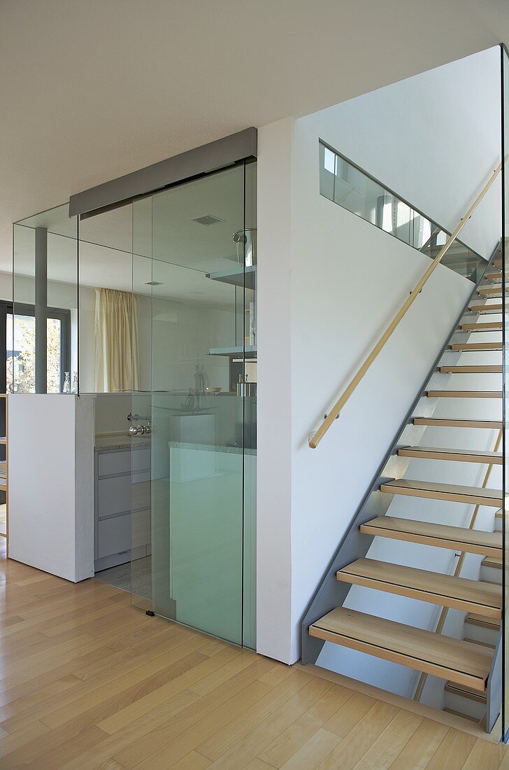 Moderne Küche mit Glaswand und Treppe mit offenen Holzstufen