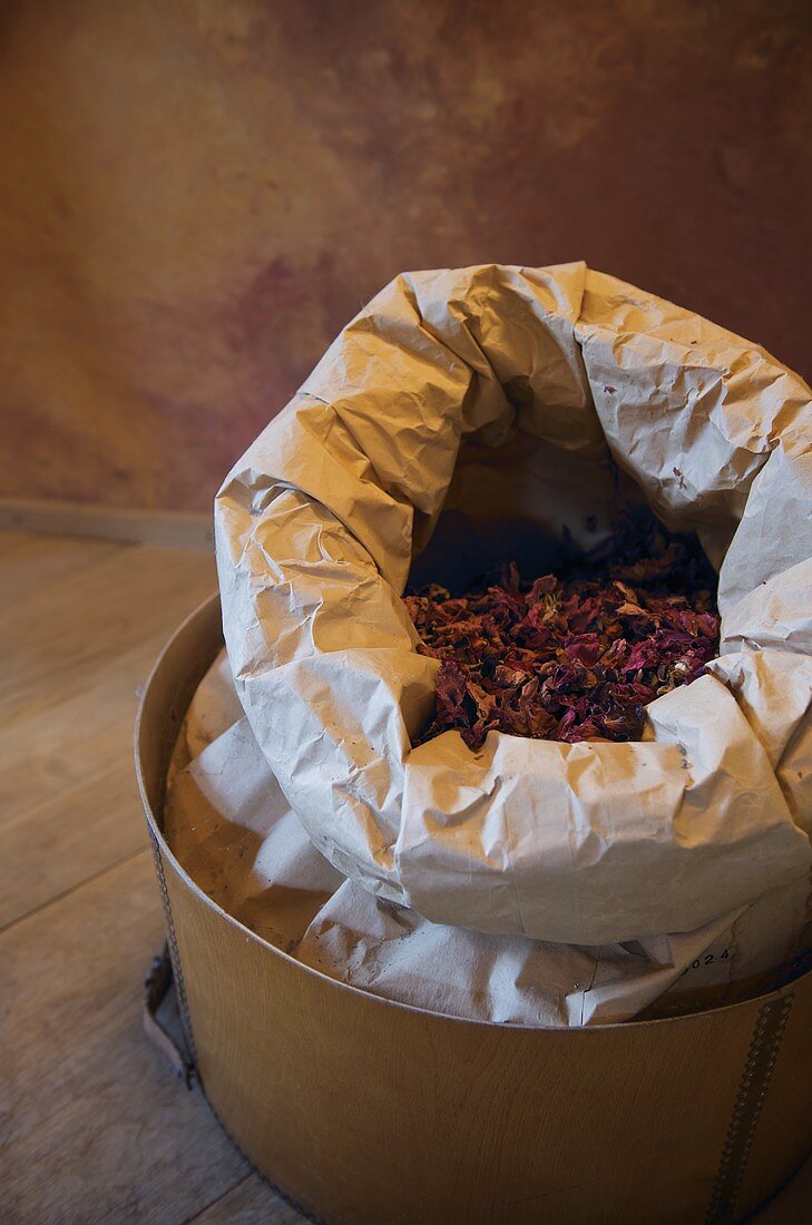 Open paper bag with dried petals in a wooden container