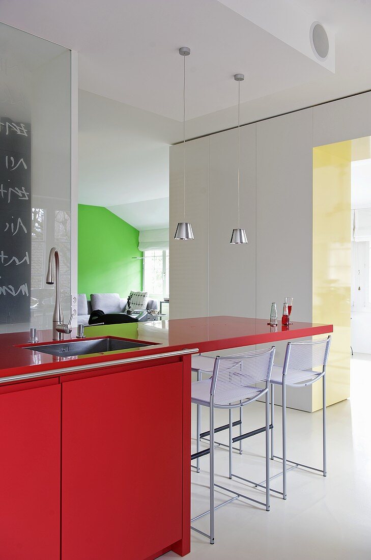 Roter Küchenblock mit auskragender Platte und Barhocker in moderner Küche