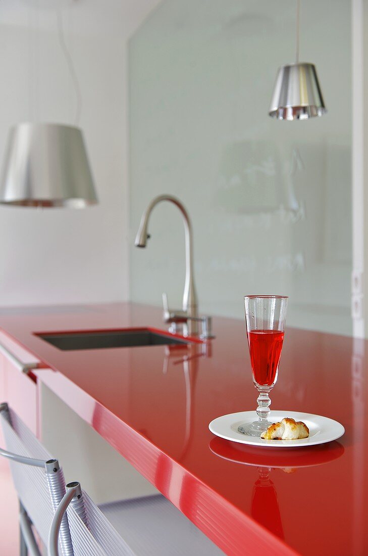 Glass of red drink on plate on kitchen worktop
