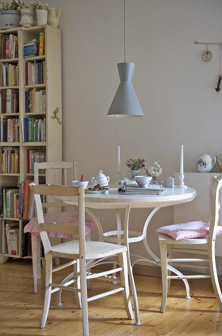 Kaffeepause auf weißem Tisch mit Holzstühlen und Hängelampe im Fifties Stil