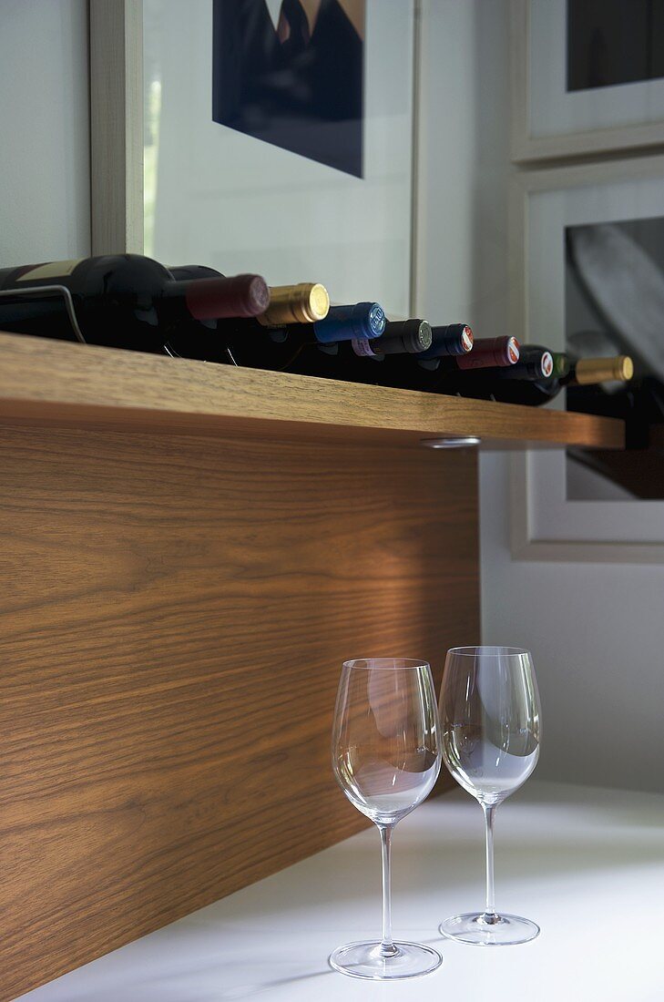 Weinflaschen auf Holzregal und Weingläser