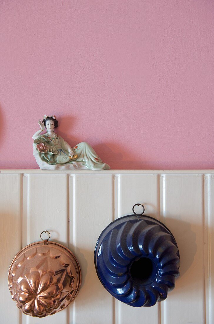 Two old-fashioned cake tins hanging on white wooden panelling