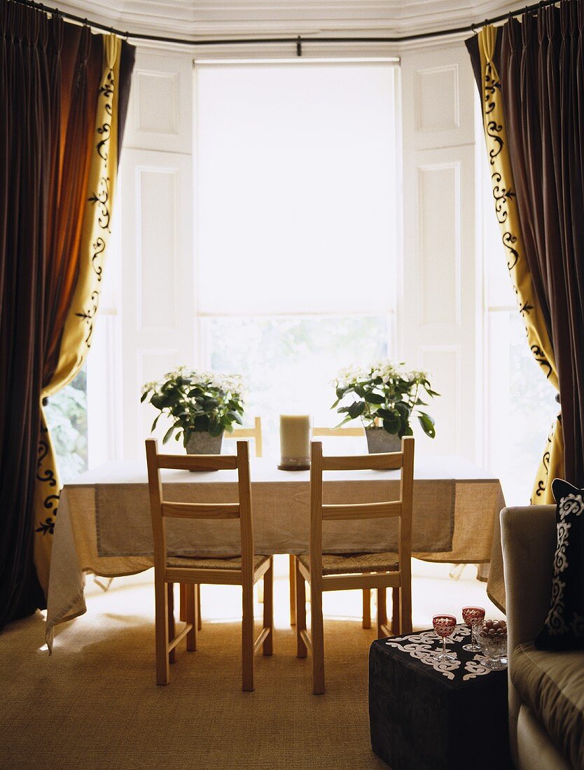 Dining room with table and chairs in window with drapes