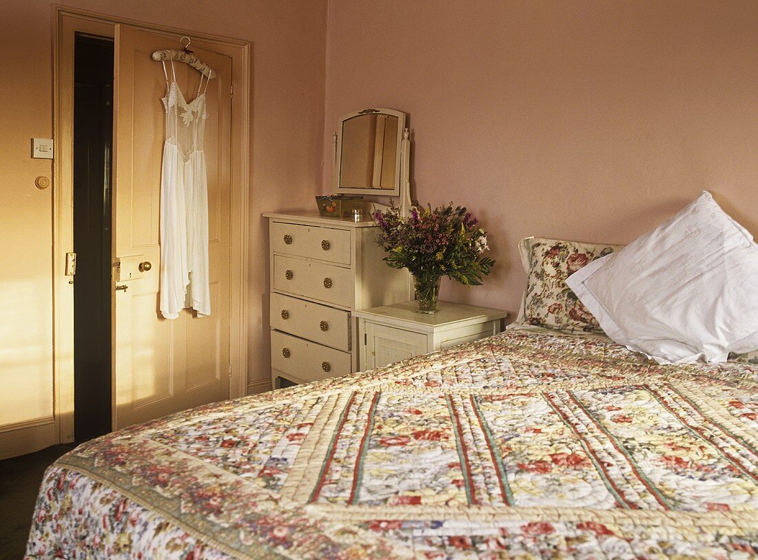 Double bed with floral pattern cover in peach bedroom