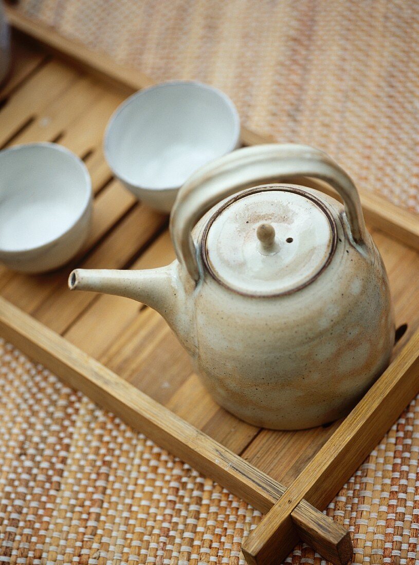 Ceramic teapot and beakers on wooden tray