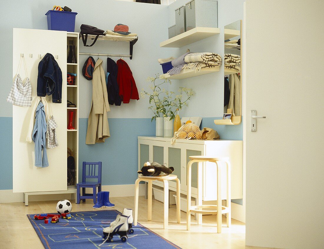 Garderobenschrank und offene Garderobe neben Sideboard im blau getönten Vorraum