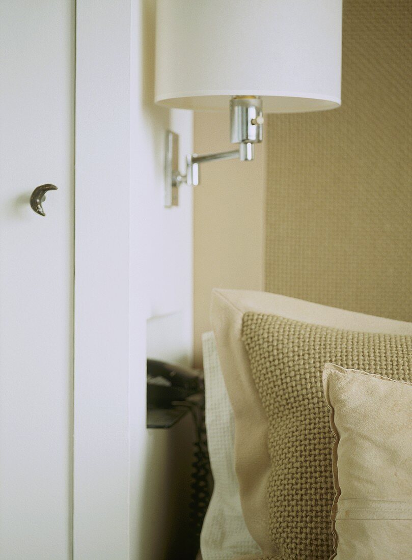 A detail of a wall mounted light fitting, neutral, natural textured cushions,