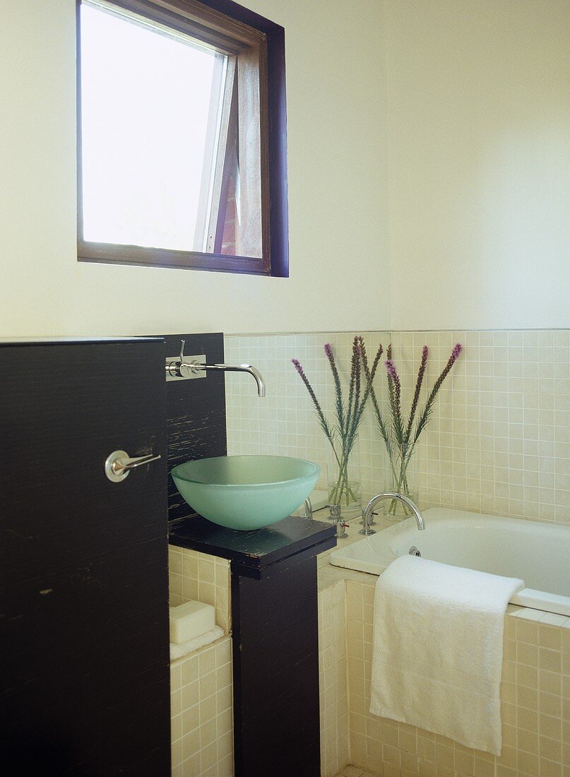 Waschschüssel aus Glas neben Badewanne und Fenster im modernen Bad