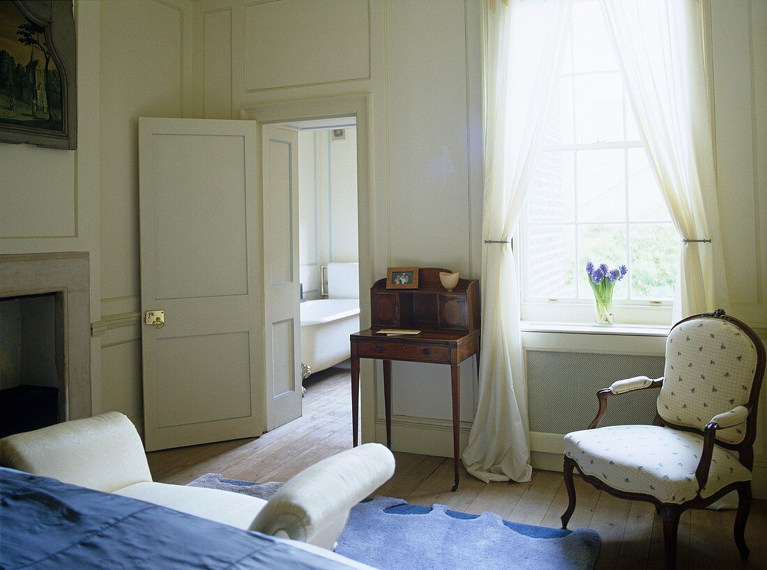 Blue and white bedroom with antique furniture and panelled walls.