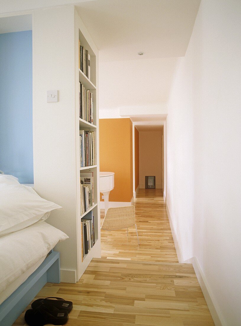 A view of a modern, open plan minimalist bedroom, wooden floor, shelving,